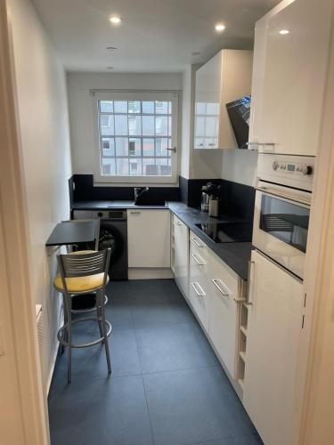 une cuisine avec des armoires blanches et une table et une chaise dans l'établissement Bel appartement Fragonard, à Charenton-le-Pont