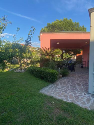a building with a stone walkway next to a yard at Villa Rita Guest House Torvaianica in Torvaianica