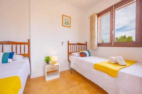 Dos camas en una habitación con ventana. en Bungalow Salud - PlusHolidays, en Calpe