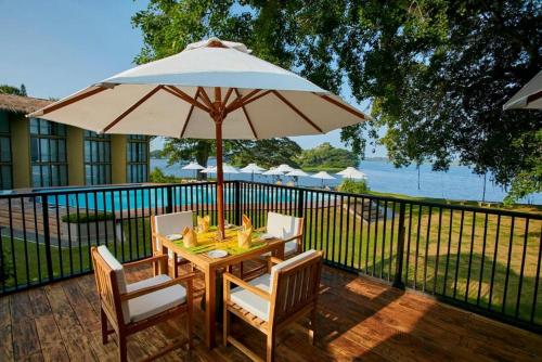 a table and chairs with an umbrella on a deck at EKHO Safari Tissa in Tissamaharama