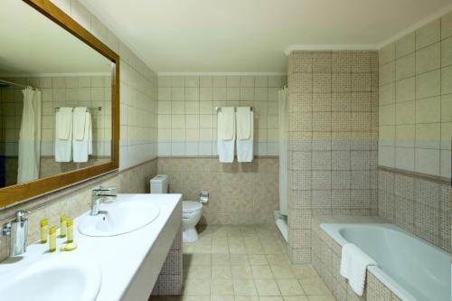 a bathroom with two sinks and a tub and a toilet at Mitsis Alexander the Great Hotel in Kriopigi