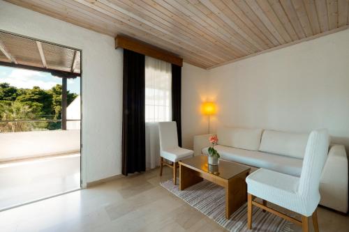 a living room with a couch and a table and chairs at Mitsis Alexander the Great Hotel in Kriopigi