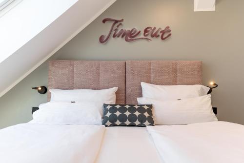 a bed with white pillows and a sign that reads time out at KOOS Hotel&Apartments - City Aparthotel in Munich