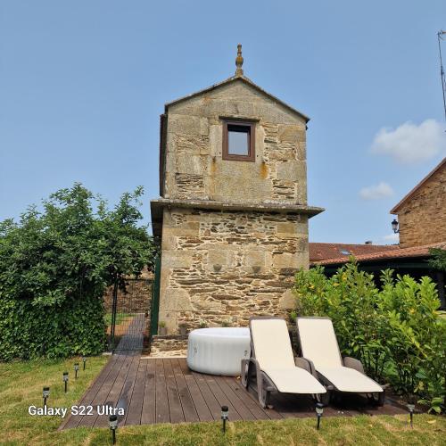 a group of chairs sitting on a deck in front of a building at Casa Horreo lar san Adrián in A Coruña
