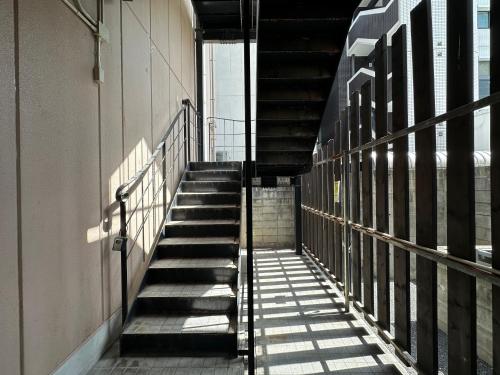 a staircase in a building with its shadows on the wall at goom Monthly Nakasu JOJO in Fukuoka