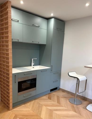 une cuisine avec des armoires bleues, un tabouret et un évier dans l'établissement Clinfoc 21, à La Grande Motte