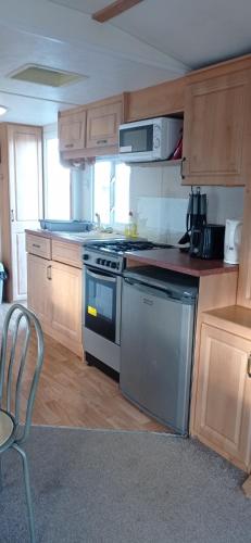 a kitchen with wooden cabinets and a stove top oven at Beachside, Family-friendly, WiFi, 6 berth Caravan 19 in Ingoldmells in Ingoldmells