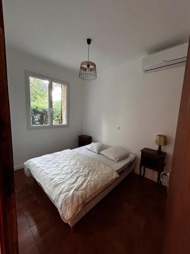 une chambre blanche avec un lit et une fenêtre dans l'établissement Maison familiale mer et montagne, à Santa-Lucia-di-Moriani