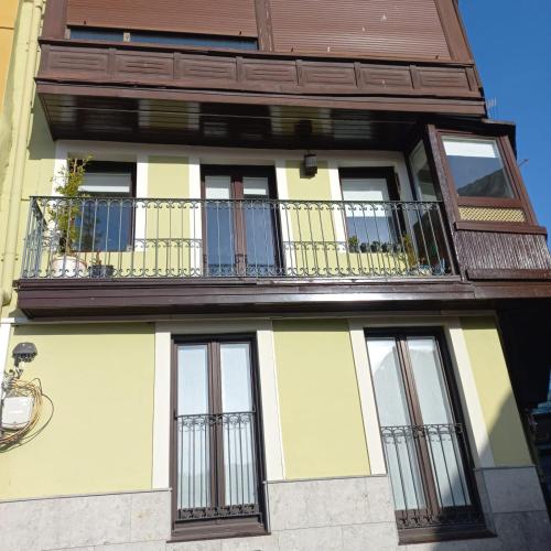 a yellow and white building with a balcony at Apartamento Kuttun Bermeo in Bermeo