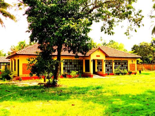 a yellow house with a tree in the yard at Gram Bangla Retreat in Kolkata