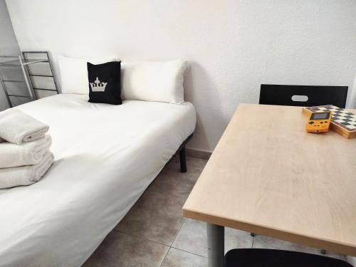 a room with two beds and a wooden table at La Habitación de Santa Eulalia habitación privada in Hospitalet de Llobregat