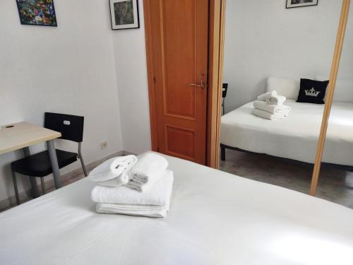 a bedroom with a bed with towels and a mirror at La Habitación de Santa Eulalia habitación privada in Hospitalet de Llobregat