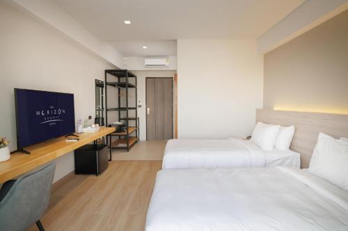 a hotel room with two beds and a tv at The Horizon Groove Hotel in Ban Khlong