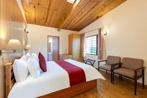une chambre avec un grand lit et deux chaises dans l'établissement Lions Den Estate 7 BD Ramgarh serviced Villa BBQ, à Rāmgarh