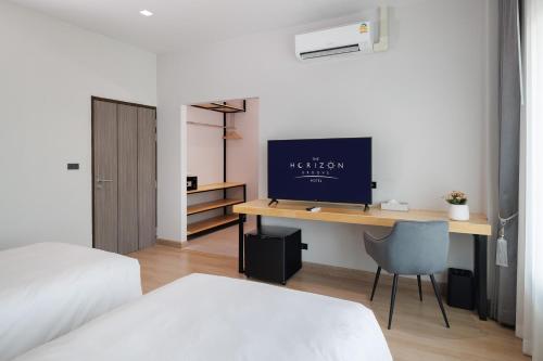 a bedroom with a desk with a television on it at The Horizon Groove Hotel in Ban Khlong