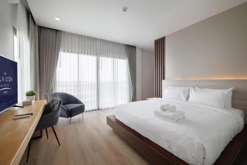 a bedroom with a bed with a desk and a chair at The Horizon Groove Hotel in Ban Khlong