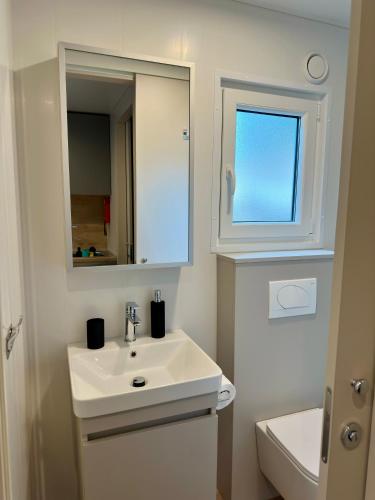 a white bathroom with a sink and a mirror at Mobile Homes - Camping Melany Umag in Lovrečica