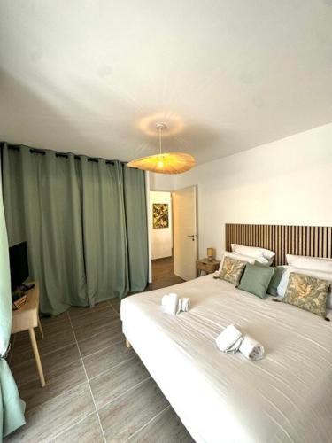 - une chambre avec un grand lit blanc et un lustre dans l'établissement T2 confort - résidence privée, à Propriano