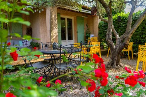 a table and chairs in front of a house with red flowers at Hotel Les Oliviers in Draguignan