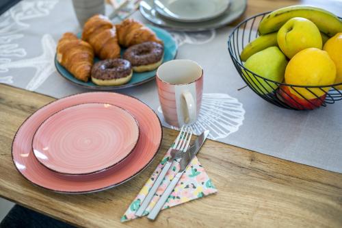 a table topped with plates and a bowl of fruit at Palmtrees Apartments in Afantou