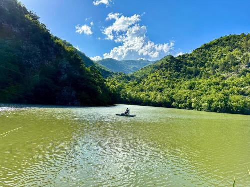a person in a boat on a lake in the mountains at Stay Hovq in Dilijan