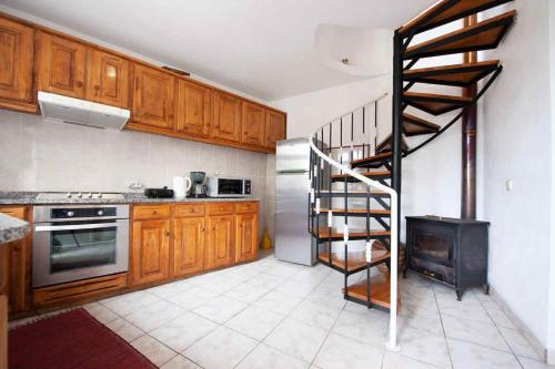 a kitchen with wooden cabinets and a spiral staircase at Casa Reis in Santana