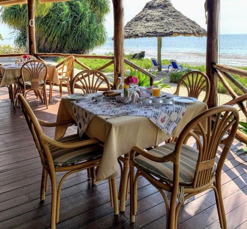 een eettafel en stoelen op een terras met uitzicht op de oceaan bij Barry's Beach Resort in Mkwaja