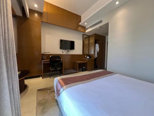 a bedroom with a bed and a desk with a tv at Jol Torongo in Cox's Bazar