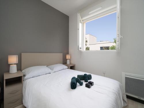 - une chambre dotée d'un grand lit blanc avec deux chaussures dans l'établissement La Dune N52 - Villa 3P6, à Sérignan