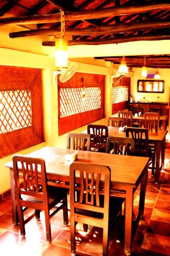 a dining room with wooden tables and chairs at Gram Bangla Retreat in Kolkata