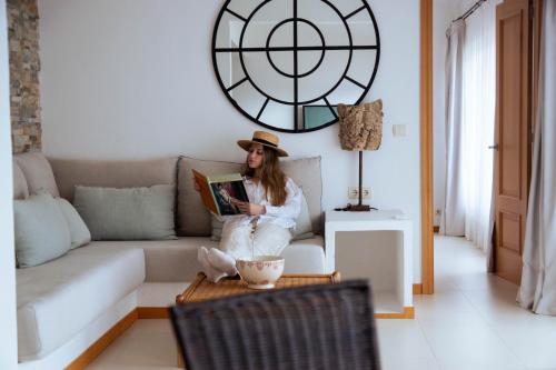 a woman sitting on a couch reading a book at BYPILLOW Cap Sa Sal in Begur