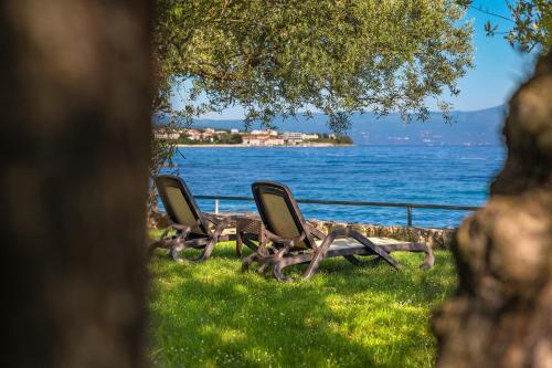 two chairs sitting on the grass near the water at Hotel Vila Rova in Malinska