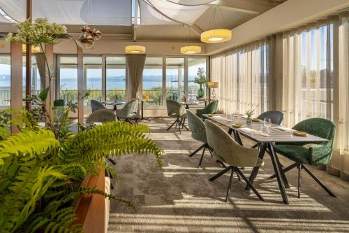 a dining room with tables and chairs and plants at Hotel Vila Rova in Malinska