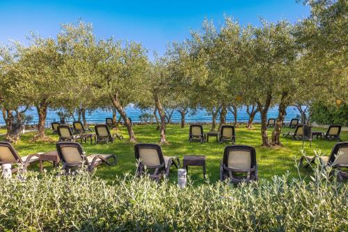 a group of chairs sitting in the grass near the water at Hotel Vila Rova in Malinska