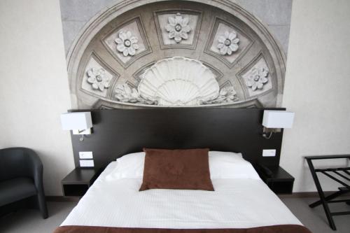 a bedroom with a white bed with a decorative headboard at Logis Hôtel - La Chambre d'Amiens in Amiens