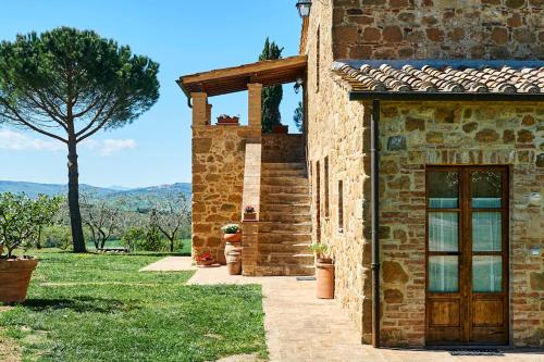 a stone house with a door and a tree at Agriturismo Il Casalino in Pienza