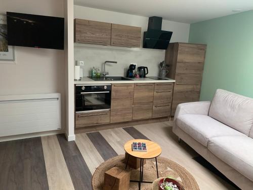 a living room with a couch and a kitchen at L'étape de Marcel - Aymé in Avoine