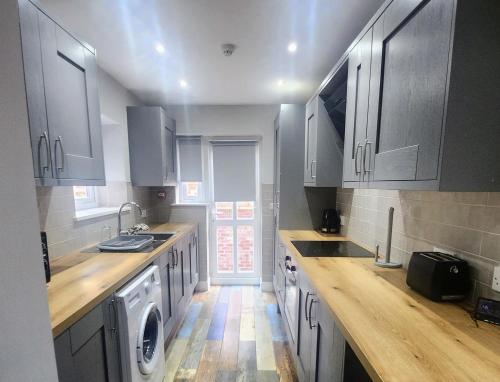 a kitchen with white cabinets and a washer and sink at The Red Lounge Rooms Near Anfield in Liverpool