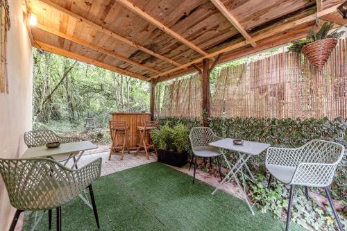 a patio with chairs and tables and a fence at Gîte zen dans les bois in Blésignac