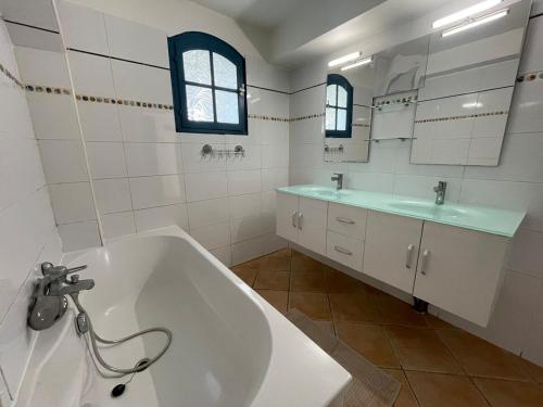 La salle de bains blanche est pourvue d'une baignoire et de deux lavabos. dans l'établissement villa Dolce Vita en Provence, à Ceyreste