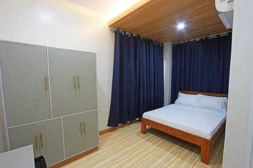 a bedroom with a bed and a blue curtain at Passage Point Guest House in Dauin