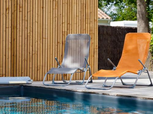 two chairs sitting next to a swimming pool at Holiday Home Le Pré Tarin by Interhome in La Bernerie-en-Retz