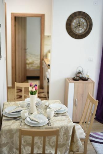 a dining room table with plates and flowers on it at NeVa Apartman in Rakari