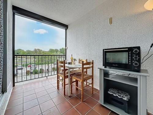 d'un salon avec une table et une télévision ainsi que d'un balcon. dans l'établissement Apartment Le Lagon Bleu-7 by Interhome, au Grau-du-Roi