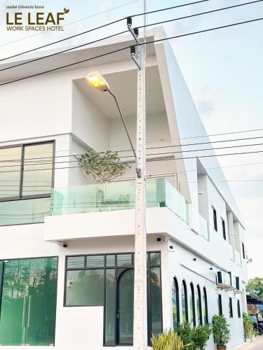 a white building with a street light in front of it at Leleaf Work Spaces Hotel - เลอลีฟ เวิร์คสเปซ โฮเทล in Sakon Nakhon
