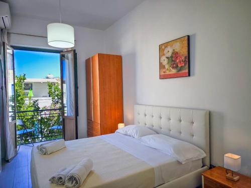 a bedroom with a large white bed with a balcony at CasaVacanzeAurora in San Vito lo Capo