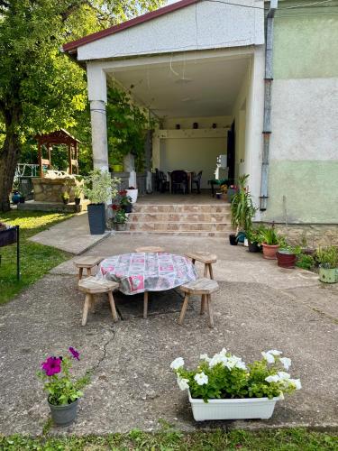 a table and benches in front of a garage with flowers at Idila pod Rtnjem - Najam cele vikendice sa bazenom in Ilino