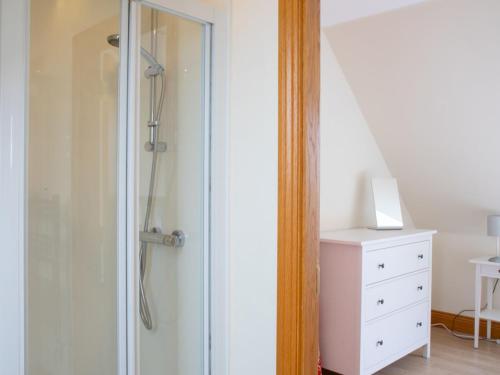 a shower with a glass door next to a white dresser at Chalet Solace by Interhome in Flashader