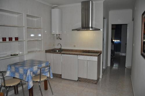 a kitchen with a sink and a table with chairs at Apartamentos La Venta in Soto de Cangas