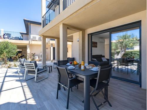 un patio avec une table et des chaises sur une terrasse dans l'établissement Apartment Foce Dell Edera-3 by Interhome, à Bonifacio